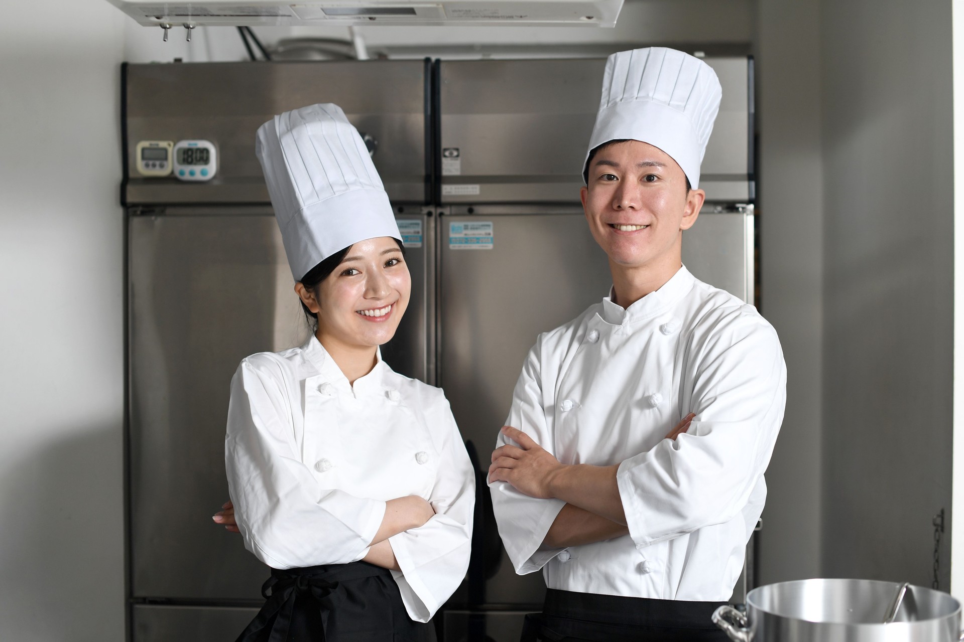 Young Asian female cook and male cook are arm in arm in the kitchen