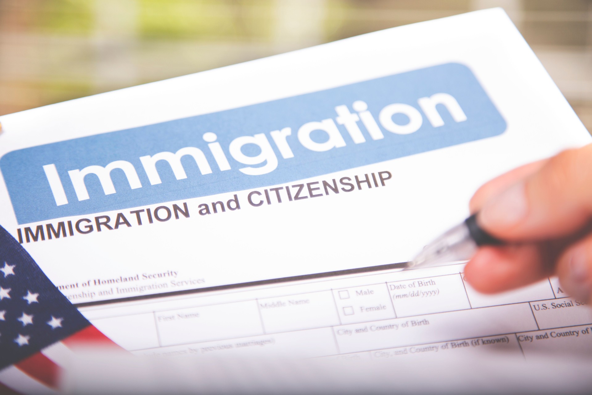 Person filling out American immigration, citizenship forms. USA flag.